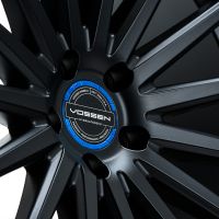 A dark metallic car wheel with intricate spokes displays a central logo reading "VOSSEN HYBRID FORGED" and surrounding text: "VOSSEN WHEELS EST. 2006 U.S.A. PRECISION - PERFORMANCE - PRECISION."