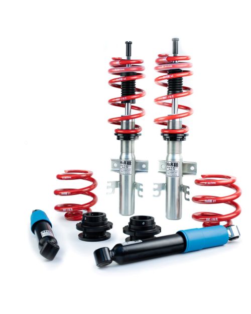 Red springs and silver struts are assembled and standing upright. Beside them, black and blue shock absorbers and additional springs lie on a white background. Labels include "H&R" and spring specifications.